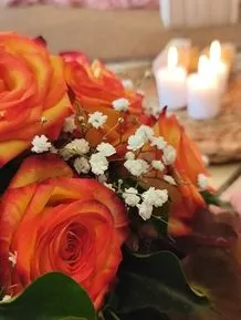 Trauerblumengebinde mit roten Rosen und Kerzen